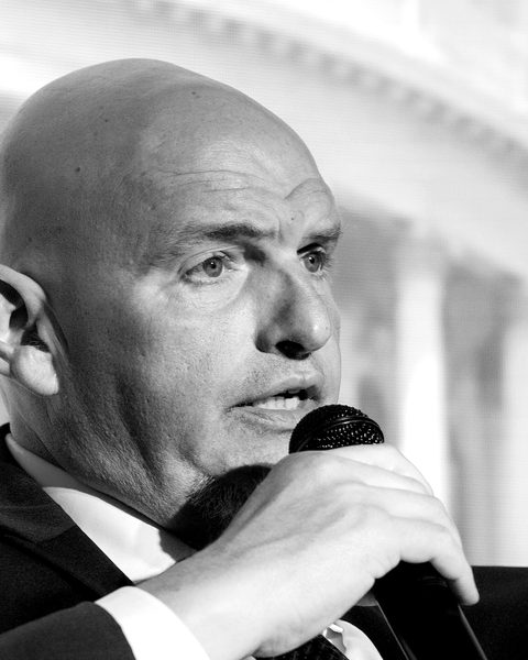 Senator John Fetterman speaks into a microphone on the Summit stage.