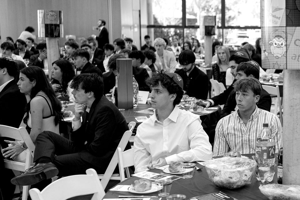 Students at dinner tables in a crowded hall.