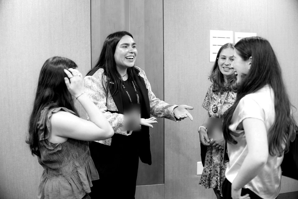 Four students talk and laugh together in a hallway at the Summit.