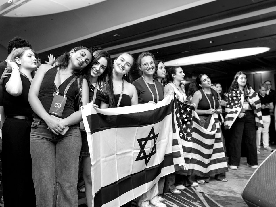 A line of students stands shoulder to shoulder holding Israeli and American flags at the Summit.