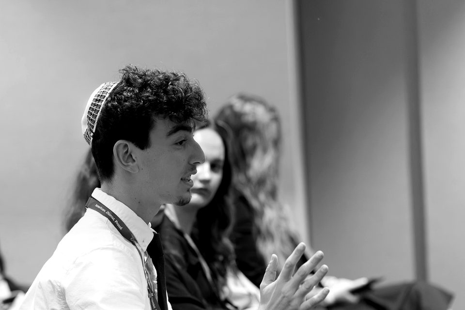 A student in a kippah speaks during a Summit session as other students listen behind him.